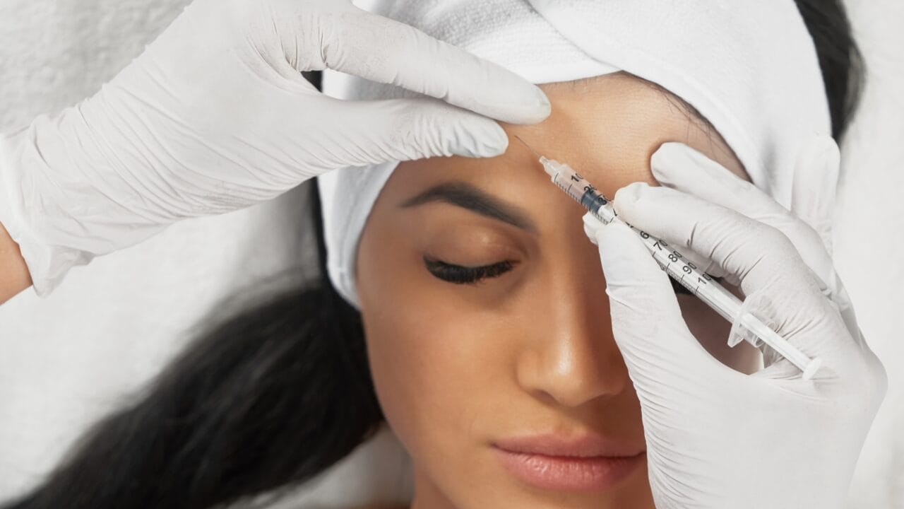 Dermatologista realizando aplicação de toxina botulínica para tratamento de rugas de expressão.